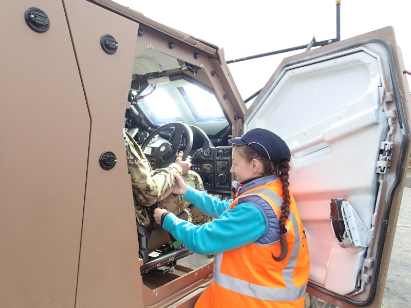 Dr Melanie Franklyn making final adjustments to an anthropomorphic test device seated inside a Hawkei vehicle in preparation for a blast test.