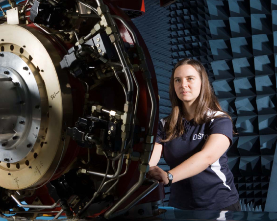 A photograph of a DST Group researcher checking Servo valve voltages on the Flight Motion Simulator as part of the pre-trial checks before a Hardware-in-the-Loop simulated flight engagement.