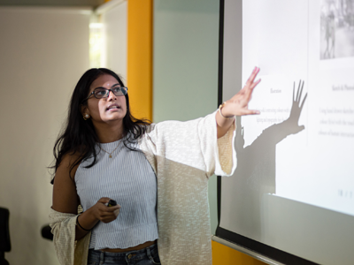 An image of a woman at a whiteboard, explaining her work