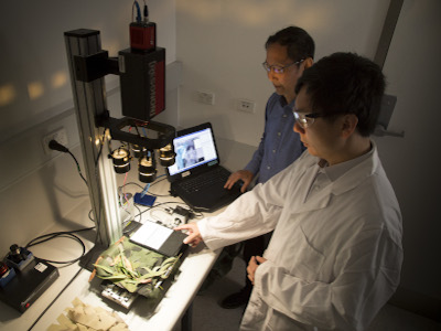 DST scientists Jay Yu (foreground) and Bin Lee using a benchtop hyperspectral imaging camera to conduct material reflectance property measurements.