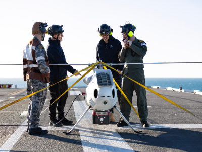 S100 Crew from 822X Squadron and scientists from Defence Science and Technology Group discuss the S100 Bathymetric LiDAR Sensor trials on the Flight Deck of HMAS Adelaide during Exercise Sea Raider 23.