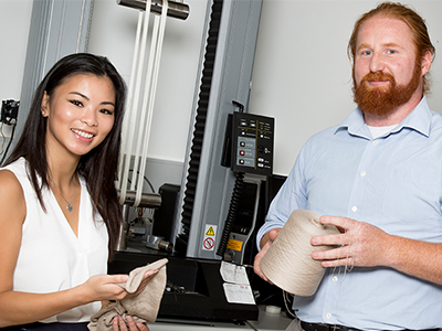 Vanessa Ha and Mark Ryan with the equipment used to stretch the yarn samples used in their shape-memory polymer research. Vanessa Ha and Mark Ryan with the equipment used to stretch the yarn samples used in their shape-memory polymer research.