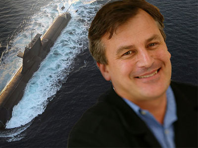 Dr Alex Zelinsky in front of a large photograph of a submarine.