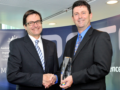 Greg Combet shaking hands with Dr Gordon Frazer after presenting him with his award.