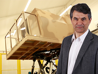 Eugene Aidman in front of the DST Land Motion Platform vehicle simulator