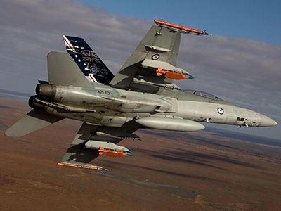 A Royal Australian Air Force F/A-18 Hornet in flight with two JDAM-ER 500lb bombs and two Time Space Position Information pods.