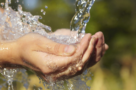 An image of water flowing onto cupped hands.