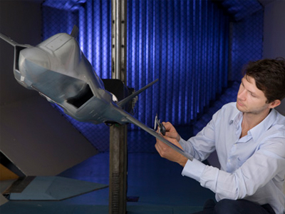 A model of the Joint Strike Fighter in the Transonic Wind Tunnel. The model was built by our Science Engineering Services team. Photo of a staff member working on a model of the JSF aircraft in the Transonic Wind Tunnel.