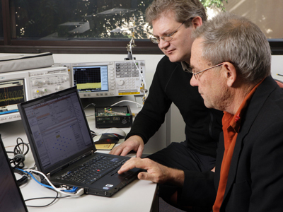 Two men working on a laptop computer.