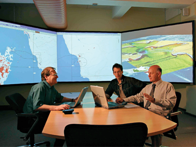 Inside the Concept Exploration and Analysis Laboratory (CEAL) at DST Group in Sydney. An image of three men at the Concept Exploration and Analysis Laboratory CEAL at DST Group in Sydney, discussing naval technology