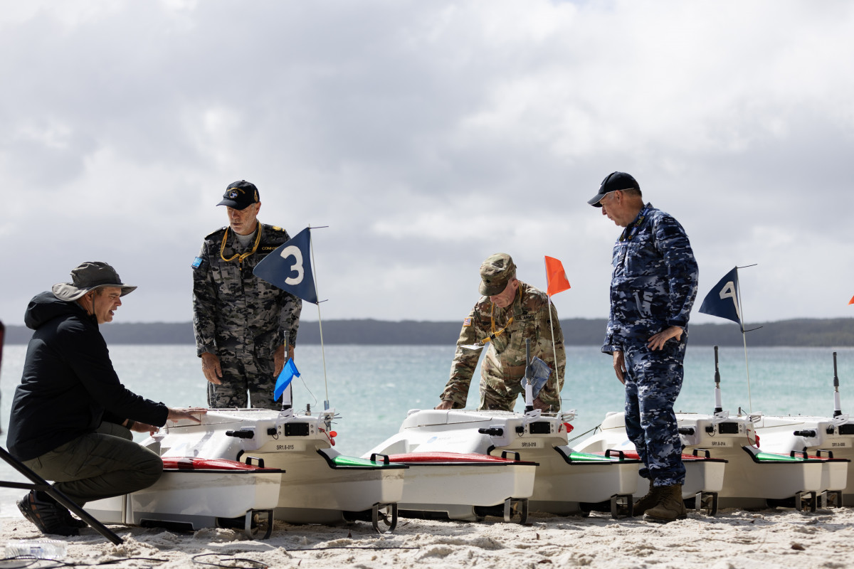 (From Left) Michael Novitzky, Warrant Officer Richard Comfort, Lieutenant Colonel Charles O'Donnell and Squadron Leader Robert Morris discuss the SWARMS Sea Robotics unmanned vehicles capability during the Technical Cooperation Program AI Strategic Challenge 2023 at HMAS Creswell, Jervis Bay Territory.