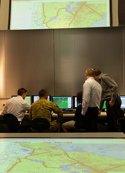 Defence members gathered around computers at a Defence wargame facility