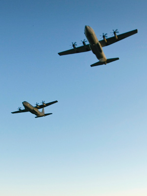 Two C-130J aircrafts fly overhead.