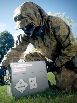 An officer, wearing protective material, examines a hazardous box as part of a safety demonstration.