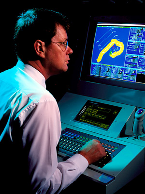 An image of a man sitting in front of a computer screen.