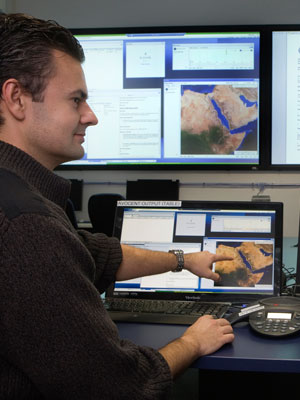 Two DST Group researchers working in the ELIIXAR environment. Two DST Group researchers working in front of several computer screens.