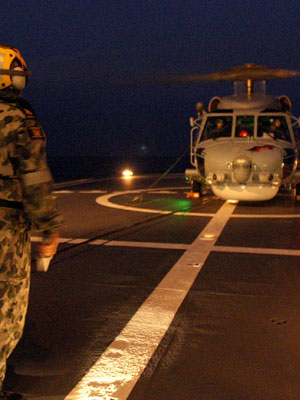 Flight deck marshal, Petty Officer Steward Jason "Moo Moo" Aitken prepares to direct HMAS Darwin's Seahawk Helicopter from HMAS Perth's flight deck during Exercise Kakadu 2012.