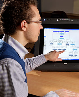 A young man pointing at a computer screen