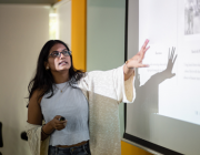 An image of a woman at a whiteboard, explaining her work