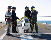 S100 Crew from 822X Squadron and scientists from Defence Science and Technology Group discuss the S100 Bathymetric LiDAR Sensor trials on the Flight Deck of HMAS Adelaide during Exercise Sea Raider 23.