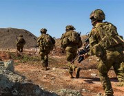 A photo of soldiers running over rough terrrain.