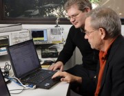 Two men working on a laptop computer.