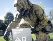 A soldier in protective clothing handling a dangerous item.