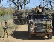 A soldier (left) alongside a Bushmaster vehicle A soldier (left) alongside a bushmaster vehicle.