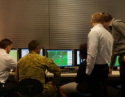 Defence members gathered around computers at a Defence wargame facility