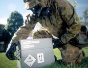 An officer, wearing protective material, examines a hazardous box as part of a safety demonstration.