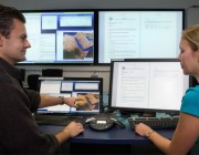 Two DST Group researchers working in the ELIIXAR environment. Two DST Group researchers working in front of several computer screens.