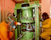 Two scientists in protective clothing handling insensitive munitions. Two scientists in protective clothing handling insensitive munitions.