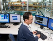 An image of a DST Group scientist at a computer, with the underwater facility in the background.