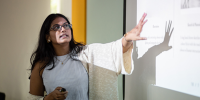 An image of a woman at a whiteboard, explaining her work