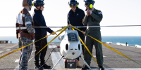 S100 Crew from 822X Squadron and scientists from Defence Science and Technology Group discuss the S100 Bathymetric LiDAR Sensor trials on the Flight Deck of HMAS Adelaide during Exercise Sea Raider 23.
