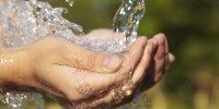 An image of water flowing onto cupped hands.