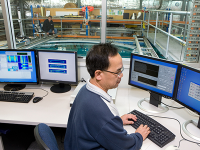 An image of a DST Group scientist at a computer, with the underwater facility in the background.